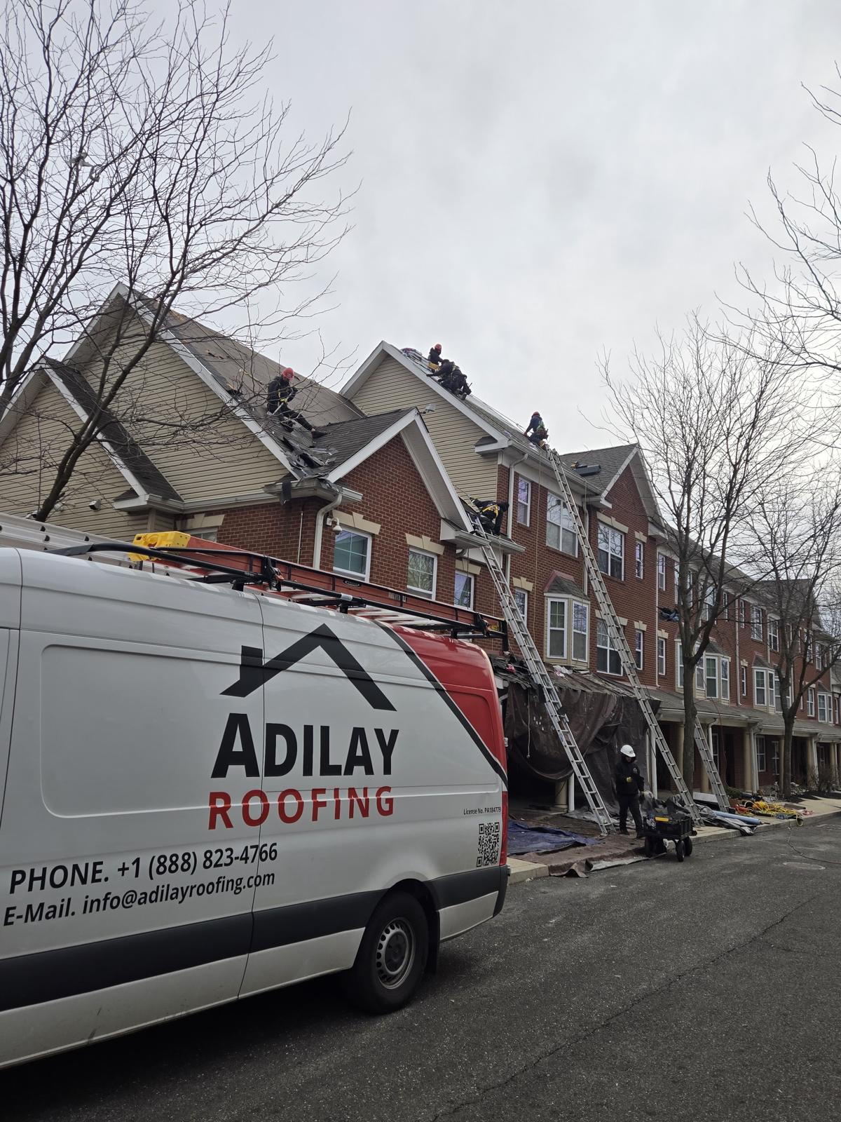Adilay Roofing van and crew working on a multi-unit roof replacement in Philadelphia